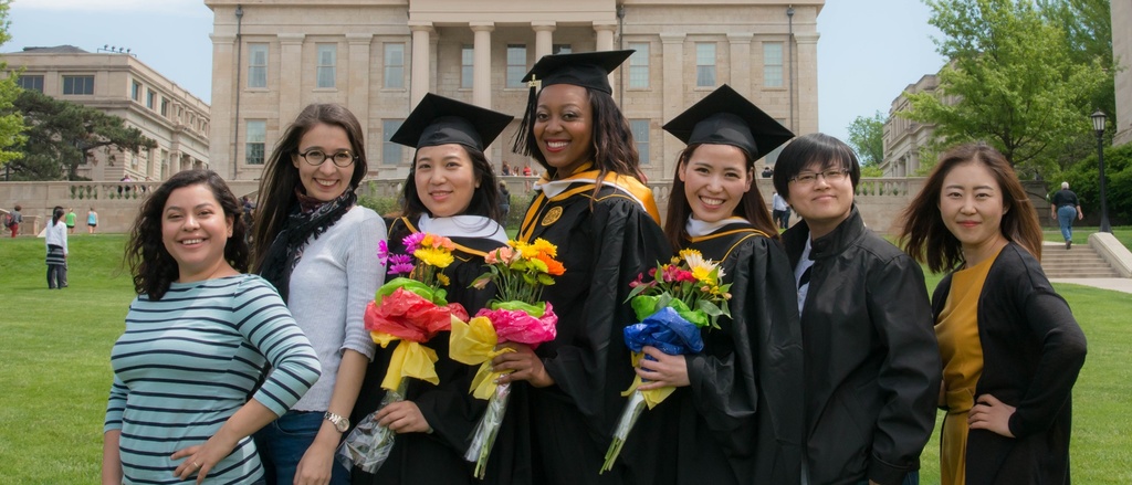 International Grads posing in front of the Old Capitol in caps and gowns